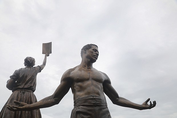 Two new 12-foot bronze statues comprising the Emancipation and Freedom Monument are unveiled and dedicated Wednesday in front of several hundred people at Brown’s Island.
