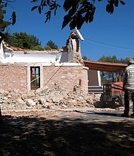 Residents pass next to a damaged Greek Orthodox chapel after a strong earthquake in Arkalochori village on the southern island of Crete, Greece on Monday, September 27.
Mandatory Credit:	Harry Nakos/AP