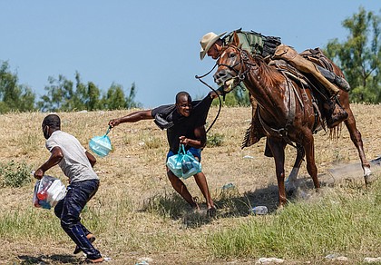 A U.S. Border Patrol agent on horseback tries to stop a Haitian migrant