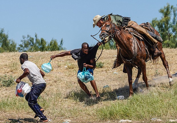 A U.S. Border Patrol agent on horseback tries to stop a Haitian migrant