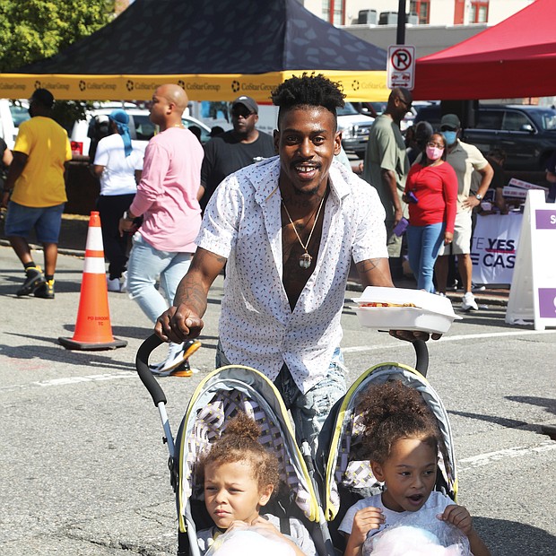 Riding along with Dad-Tre Powell of Richmond grew up attending the annual 2nd Street Festival in Jackson Ward. Last Saturday, he was passing along the tradition to his children, Levi Powell, 4, left, and Olivia Powell, 5, who were enjoying the treats as much as the music.