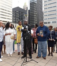 Attorney Ben Crump, center, holds Zayden Joseph, 6, the great-grandson of the late Henrietta Lacks, during a news conference Monday outside of the federal courthouse in Baltimore with Mrs. Lacks’ family members and other attorneys. The Lacks estate is filing suit against a Massachusetts company, Thermo Fisher Scientific, for using Mrs. Lacks’ cells, known as HeLa cells, without the estate’s permission.