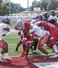 With a gaggle of players clinging to him, Virginia Union University’s Jada Byers pushes his way across the goal line last Saturday for a touchdown. It was the Panthers sole touchdown against Shaw University.