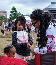 Faith Walker helps her 2-year-old niece, Legacy, and daughter, Phoenix, 6, sanitize their hands at the Richmond Folk Festival on brown’s Island last weekend. thousands of people attended the three-day cultural extravaganza, where people were asked to wear masks, use hand sanitizer and keep socially distanced to help curb the spread of COVID-19. Free COVID-19 vaccines and hand sanitizer stations were available at the site for festival goers during the weekend.