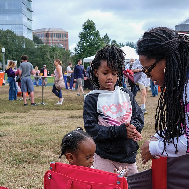 Faith Walker helps her 2-year-old niece, Legacy, and daughter, Phoenix, 6, sanitize their hands at the Richmond Folk Festival on brown’s Island last weekend. thousands of people attended the three-day cultural extravaganza, where people were asked to wear masks, use hand sanitizer and keep socially distanced to help curb the spread of COVID-19. Free COVID-19 vaccines and hand sanitizer stations were available at the site for festival goers during the weekend.
