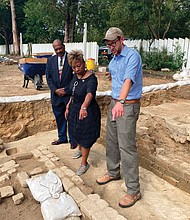 Dr. Reginald F. Davis, left, pastor of First Baptist Church in Williamsburg, Connie Matthews Harshaw, a member of First Baptist, and Jack Gary, Colonial Williamsburg’s director of archaeology, stand Oct 6 at the brick-and-mortar foundation of the old church unearthed in Williamsburg’s historic area.