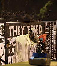 Free Egunfemi of Untold RVA and visitors pay homage to Gabriel near a wall of placards at the African Burial Ground in Shockoe Bottom commemorating the freedom fighter. The placards were installed by Untold RVA.