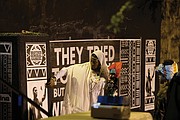 Free Egunfemi of Untold RVA and visitors pay homage to Gabriel near a wall of placards at the African Burial Ground in Shockoe Bottom commemorating the freedom fighter. The placards were installed by Untold RVA.