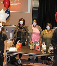 George Wythe High School students Deanna Martinez, left, and Oran Christian, right, receive goodie bags filled with education tools after participating in an orientation Monday of the newly funded Bulldog Enrichmond Academy. Standing behind the table are George Wythe parent participants, from left, Yakysha Langhorne, Tina Wooden and Rosemarie Edmonds.