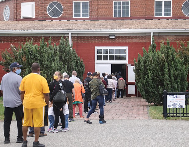 A long line stretches out the door of the Old Dominion building at the Richmond Raceway on tuesday, the first day for the reopened Community Vaccination Center where people can get booster shots or their first or second doses of the COVID-19 vaccine.