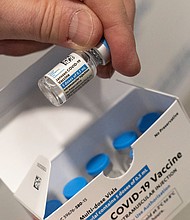 Experts say those who received the Johnson & Johnson one-dose vaccine are "awfully well protected," but should still get another shot for maximum safety, and pictured, a pharmacist holds a vial of the Johnson & Johnson Covid-19 vaccine at a hospital in New York.
Mandatory Credit:	Mark Lennihan/AP