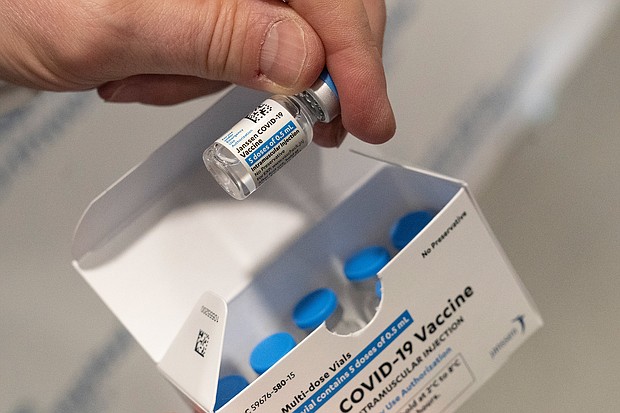Experts say those who received the Johnson & Johnson one-dose vaccine are "awfully well protected," but should still get another shot for maximum safety, and pictured, a pharmacist holds a vial of the Johnson & Johnson Covid-19 vaccine at a hospital in New York.
Mandatory Credit:	Mark Lennihan/AP