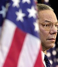 Secretary of State Colin Powell looks on as President George W. Bush addresses State Department employees at the Washington headquarters on Feb. 15, 2001.