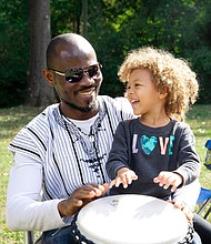 Three-year-old Zara takes a short drumming lesson with her father, Babs, an artist originally from West Africa who now lives in Richmond. Babs, whose paintings include landscapes and African wildlife, was among the bevy of artists participating last Saturday in the 2nd Annual Art Under the Pines exhibition at Pine Camp Cultural Arts & Community Center’s Sculpture Garden. Zara and her older sister, Chali, 9, kept their father company during the event.