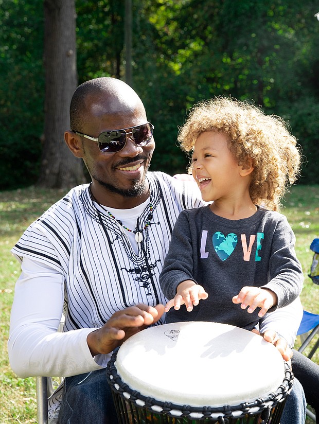 Three-year-old Zara takes a short drumming lesson with her father, Babs, an artist originally from West Africa who now lives in Richmond. Babs, whose paintings include landscapes and African wildlife, was among the bevy of artists participating last Saturday in the 2nd Annual Art Under the Pines exhibition at Pine Camp Cultural Arts & Community Center’s Sculpture Garden. Zara and her older sister, Chali, 9, kept their father company during the event.