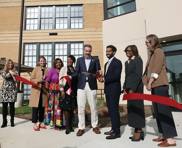 The former Baker Elementary School in Gilpin Court has been remodeled and is now a 50-unit apartment complex serving low-income seniors with modern appliances, gleaming countertops, hardwood floors and a fitness center. Gov. Ralph S. Northam, center, joins Brian McLaughlin, president of Enterprise Community Development’s community development division, and other dignitaries to cut the ribbon at the grand opening Oct. 28 for the new complex at 100 W. Baker St.