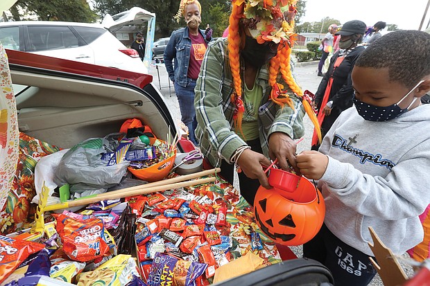 It was a sweet Halloween for Richmond youngsters, including 6-year-old Timothy Townes, who attended “Trunk or Treat” hosted by Moore Street Missionary Baptist Church last Saturday in the church parking lot at 1408 W. Leigh St. in the Carver community. The youngsters enjoyed trick or treating by going from trunk to trunk of cars and vehicles decorated for the event and supplied with loads of treats. Here, barbara burton, a church member who dressed as an “urban farmer,” hands out candy from the stash in her trunk.