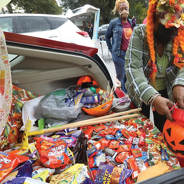 It was a sweet Halloween for Richmond youngsters, including 6-year-old Timothy Townes, who attended “Trunk or Treat” hosted by Moore Street Missionary Baptist Church last Saturday in the church parking lot at 1408 W. Leigh St. in the Carver community. The youngsters enjoyed trick or treating by going from trunk to trunk of cars and vehicles decorated for the event and supplied with loads of treats. Here, barbara burton, a church member who dressed as an “urban farmer,” hands out candy from the stash in her trunk.