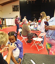 Keisha Spearman, 45, uses her cellphone camera to document her daughter, London, 5, getting her first dose of the COVID-19 vaccine at Fairfield Middle School in Henrico County. Ms. Spearman, her daughter, her mother and grandmother all had the coronavirus last year, canceling Thanksgiving.