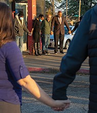 The grandfather of 9-year-old Abdul Bani-Ahmad, center, who was killed with 14-year-old Rahquan Logan in a drive-by shooting last Friday outside the OMG Convenience Store at Nine Mile and Creighton roads in East Richmond, joins hands with Richmond Police Chief Gerald M. Smith, right, and Richmond Police Officer Carol Adams, left, during a prayer vigil Wednesday afternoon outside the store. Pastor Robert Winfree of New Life Deliverance Tabernacle in South Side offered prayers at the vigil, which was organized by the Police Department and attended by many faith leaders and community members. At left, next to Officer Adams, is Robert Jefferson, a regular customer at the store who spoke highly of the grandfather and his kindness to customers.