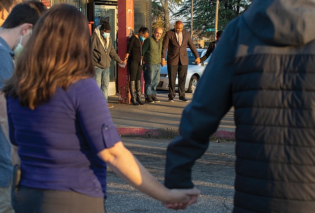 The grandfather of 9-year-old Abdul Bani-Ahmad, center, who was killed with 14-year-old Rahquan Logan in a drive-by shooting last Friday outside the OMG Convenience Store at Nine Mile and Creighton roads in East Richmond, joins hands with Richmond Police Chief Gerald M. Smith, right, and Richmond Police Officer Carol Adams, left, during a prayer vigil Wednesday afternoon outside the store. Pastor Robert Winfree of New Life Deliverance Tabernacle in South Side offered prayers at the vigil, which was organized by the Police Department and attended by many faith leaders and community members. At left, next to Officer Adams, is Robert Jefferson, a regular customer at the store who spoke highly of the grandfather and his kindness to customers.