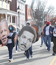 Members and staff of the Mayor’s Youth Academy carry blown up photos of notable graduates from Armstrong and Walker high schools. Here, they hold photos of former state Sen. Henry L. Marsh III, a 1952 graduate of Maggie L. Walker who served as Richmond’s first Black mayor from 1977 until 1982, and the late broadcast journalist Max Robinson Jr., an Armstrong graduate who became the first African-American network news anchor in 1978.