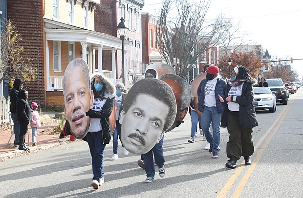 Members and staff of the Mayor’s Youth Academy carry blown up photos of notable graduates from Armstrong and Walker high schools. Here, they hold photos of former state Sen. Henry L. Marsh III, a 1952 graduate of Maggie L. Walker who served as Richmond’s first Black mayor from 1977 until 1982, and the late broadcast journalist Max Robinson Jr., an Armstrong graduate who became the first African-American network news anchor in 1978.