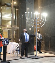 Rabbi Scott M. Nagel of Congregation Beth Ahabah lights a portion of an eight-branch menorah, the traditional symbol of the “Festival of Lights,” with support Sarah Beck-Berman, the congregation’s cantor, and Lottie, the synagogue dog. Three lights are lit to recognize the third day of Hanukkah, which started Sunday and runs through Monday, Dec. 6. The menorah also is similar to Kwanzaa’s seven-branch kinara in which candles are lit daily to mark the seven principals of the African-American cultural holiday. Kwanzaa starts Sunday, Dec. 26, and continues through New Year’s Day, Saturday, Jan. 1.