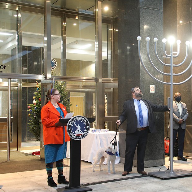 Rabbi Scott M. Nagel of Congregation Beth Ahabah lights a portion of an eight-branch menorah, the traditional symbol of the “Festival of Lights,” with support Sarah Beck-Berman, the congregation’s cantor, and Lottie, the synagogue dog. Three lights are lit to recognize the third day of Hanukkah, which started Sunday and runs through Monday, Dec. 6. The menorah also is similar to Kwanzaa’s seven-branch kinara in which candles are lit daily to mark the seven principals of the African-American cultural holiday. Kwanzaa starts Sunday, Dec. 26, and continues through New Year’s Day, Saturday, Jan. 1.