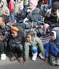 Timmesha Grimes, left, and her 5-year-old son, Malikhai Hamilton, right, and her nephew and niece, Tisiah and Tiriyah Brassell, ages 7 and 5, are engrossed in something just like the crowd around them on the curb along Broad Street last Saturday. Ms. Grimes even pulled out her cellphone to record the action. What is it? Hint: It’s an annual event that kicks off the December holidays in Downtown.