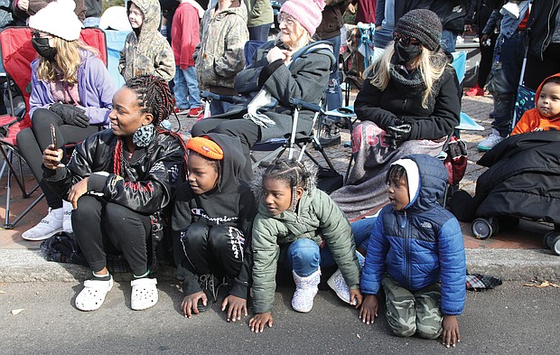 Timmesha Grimes, left, and her 5-year-old son, Malikhai Hamilton, right, and her nephew and niece, Tisiah and Tiriyah Brassell, ages 7 and 5, are engrossed in something just like the crowd around them on the curb along Broad Street last Saturday. Ms. Grimes even pulled out her cellphone to record the action. What is it? Hint: It’s an annual event that kicks off the December holidays in Downtown.