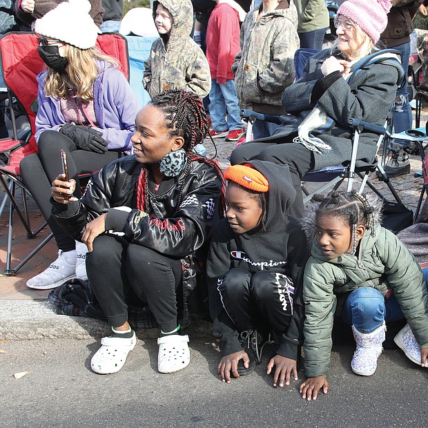 Timmesha Grimes, left, and her 5-year-old son, Malikhai Hamilton, right, and her nephew and niece, Tisiah and Tiriyah Brassell, ages 7 and 5, are engrossed in something just like the crowd around them on the curb along Broad Street last Saturday. Ms. Grimes even pulled out her cellphone to record the action. What is it? Hint: It’s an annual event that kicks off the December holidays in Downtown.
