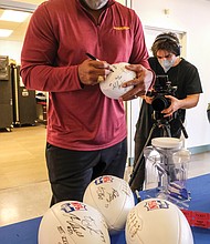 Former Washington Football Team linebacker Ravin Caldwell signs footballs for a fan give-away during a COVID-19 vaccination event last Saturday at the Bon Secours Training Center on Leigh Street in Richmond.