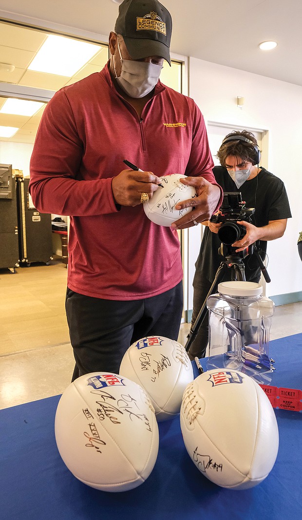 Former Washington Football Team linebacker Ravin Caldwell signs footballs for a fan give-away during a COVID-19 vaccination event last Saturday at the Bon Secours Training Center on Leigh Street in Richmond.