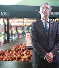 Gov. Ralph S. Northam pauses Tuesday in the produce section at The Market @ 25th in the East End before stepping up to a podium to announce several tax cuts in his proposed 2022-24 budget, including elimination of the state tax on groceries. He was joined at the news conference by State Finance Secretary Joe Flores and state Sens. Joe Morrissey and Ghazala Hashmi.