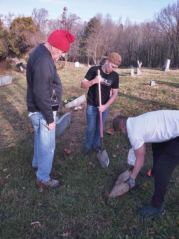 John Shuck, left, watches the work of Mormon missionaries Kelton Stacey, center, and Daniel Conlin as they carefully unearth the headstone of Callie L. Edwards, wife of William Edwards’ Sr. whose grave is adjacent. Mr. Edwards’ headstone was above ground, while that of Mrs. Edwards was covered by a three-inch layer of grass and dirt.