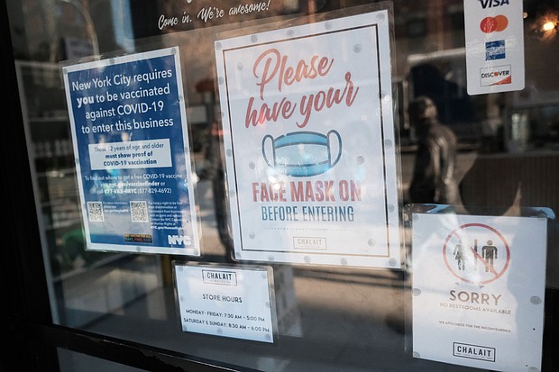A sign on the door of a coffee shop in Manhattan asks for proof of vaccination and the wearing of a mask on the day that a mask mandate went into effect in New York on December 13.
Mandatory Credit:	Spencer Platt/Getty Images