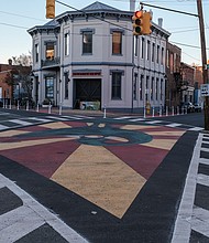 This dramatic and decorative street mural now fills the intersection at Mar- shall Street and Brook Road in Jackson Ward.
The work, painted in the red, black and green colors of the Pan-African flag, stands in front of Gallery 5, an award-winning art space housed in a historic 1849 building that served as the city’s first firehouse and police station.
Venture Richmond and the city’s Public Art Commission teamed with art spaces and businesses to develop the place-making project that was supported in part by a $25,000 grant from Bloomberg Philanthro- pies’ Asphalt Art Initiative. The project, which cost a total of $40,000, produced a new brick plaza and bike rack in front of Gallery 5.
Artist Chris Visions created the mural painted by youth participants at ART 180, a nonprofit center of youth creativity based at 114 W. Marshall St. The central figure is Sankofa, a symbol and word of the Akan people of Ghana meaning “to retrieve.” The symbol is being used as a salute to Jackson Ward’s history as the once proud center of Black business, entertainment and culture.
The mural also is connected to a custom-designed parklet that fills two parking spaces in front of ART 180. The parklet, not pictured here, is one of five the city has sought to install to promote community and businesses.
The initiative came together this year as part of marking the 150th anniversary of the city’s creation of Jackson Ward in 1871. At the time, it was a gerrymandered political district for Black voters. Venture Richmond credited the two art groups, Big Secret, Walter Parks Architects, CB Chandler Construction, Cite Design, Richmond Toolbank and Vanderbilt Properties with helping create the space.