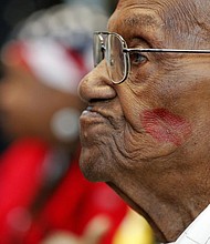 World War II veteran Lawrence Brooks sports a lipstick kiss on his cheek, planted by a member of the singing group Victory Belles, in this archive AP photo from 2019 as he celebrated his 110th birthday. Brooks died Wednesday, Jan. 5 at the age of 112.