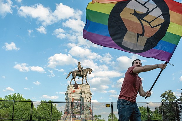 Andre Tolleris waves a banner to the honks of drivers passing by the Lee statue on Monument Avenue after a jury found a former Minneapolis Police officer Derek Chauvin guilty of the murder of George Floyd on April 20. The Lee statue on Richmond’s Monument Avenue had become a rallying point for large protests against police brutality and racial injustice following Mr. Floyd’s death in May 2020.