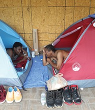 Talisha Braxton of New York, left, talks with her boyfriend, Burney Hatchett III, from within their tents set up outside the vacant Richmond Coliseum on July 11. Homeless people who had been living outside the Coliseum were moved by Richmond Police and other officials before workers began installing a fence around the Downtown venue in preparation for its demolition.