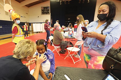 Keisha Spearman, 45, uses her cellphone camera to document her daughter, London, 5, getting her first dose of the COVID-19 vaccine at Fairfield Middle School in Henrico County on Nov. 13.The Henrico and Richmond school districts partnered with area health districts to host inoculation clinics for youngsters ages 5 to 11 after federal officials gave the green light for the vaccine to be administered to children.