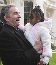 Gov. Ralph S. Northam greets 3-year-old Kamara Townes following the Jan. 7 renaming and dedication of a row of state-owned historic homes on Governor Street in Capitol Square. Both the governor and the youngster occupy a place in Virginia history. Gov. Northam is the 73rd governor of the Commonwealth, serving from Jan. 13, 2018, until his term ends this Saturday, Jan. 15. Last week, he dedicated the three newly renovated buildings, formerly known as Morson’s Row, in honor of Dr. William Ferguson “Fergie” Reid, the first Black person elected to the General Assembly following Reconstruction. One of the three buildings now called Reid’s Row was dedicated as the “Townes House,” in recognition of the Townes family that has worked at the Executive Mansion since the 1970s. Kamara is the youngest of that historic lineage. Her father, Martin C. Townes Jr., and his parents and sister are the current Townes family members serving there. Mr. Townes is the deputy butler, while his father, Martin “Tutti” Townes, is the head butler.