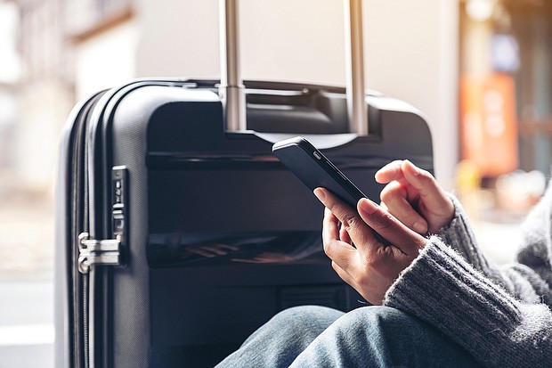 On January 19, Verizon and AT&T turned on their C-band 5G networks which are important set of radio frequencies that will supercharge the internet, and pictured, a woman sitting and using mobile phone with a black baggage for traveling.
Mandatory Credit:	Adobe Stock
