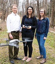 Dr. Stephanie A. Spera, center, shows off the drone she and a four-person research team that included Dr. Ryan K. Smith, left, and Elizabeth A. Zizzamia used, along with hydrology mapping, to locate possible gravesites that were unmarked in East End Cemetery. An article about the team’s investigative method was published in the International Journal of Historical Archaeology.