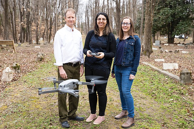 Dr. Stephanie A. Spera, center, shows off the drone she and a four-person research team that included Dr. Ryan K. Smith, left, and Elizabeth A. Zizzamia used, along with hydrology mapping, to locate possible gravesites that were unmarked in East End Cemetery. An article about the team’s investigative method was published in the International Journal of Historical Archaeology.