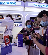 A woman is seen at the Tencent booth during a trade-in services fair in Beijing in September 2021. Stocks for the Chinese social media and gaming company Tencent, dropped after the company reported its slowest ever revenue growth.
Mandatory Credit:	Ng Han Guan/AP