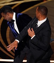Will Smith, right, hits presenter Chris Rock on stage at the Oscars on Sunday. Rock will not be pressing charges against Smith following their onstage altercation.
Mandatory Credit:	Chris Pizzello/Invision/AP
