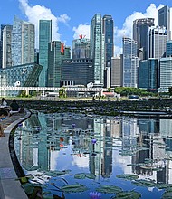 This photograph taken on June 14, 2021, shows people sitting next to a pond with a view of the skyline in Singapore.
Mandatory Credit:	Roslan Rahman/AFP via Getty Images