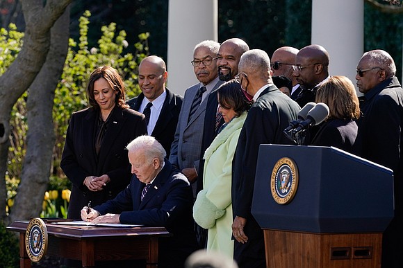 In a ceremony in the White House Rose Garden, President Biden sat at a small desk and put his signature ...